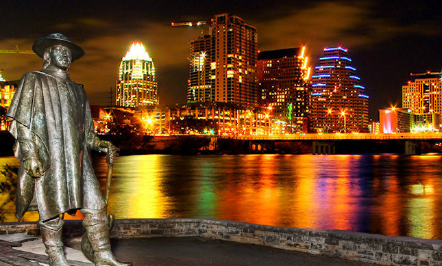 Downtown Austin skyline at night with Stevie Ray Vaughn statue and Town Lake.